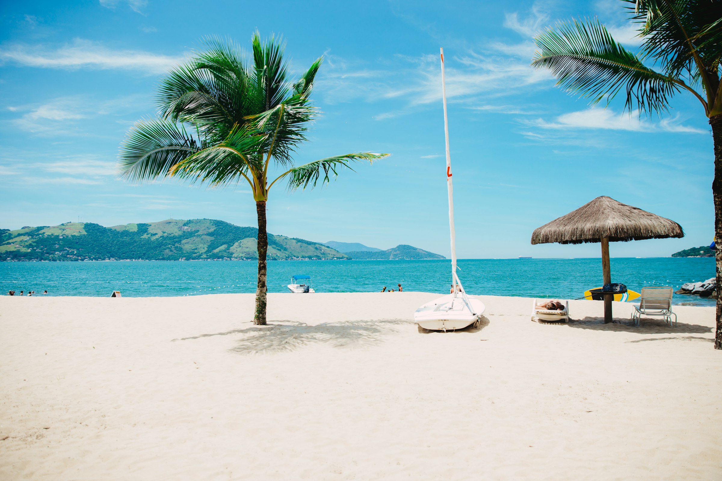 A bright Florida beach — palm trees, white sand and turquoise water under a blue sky